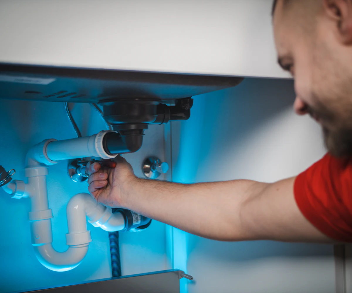 Plumber repairing pipes under a sink