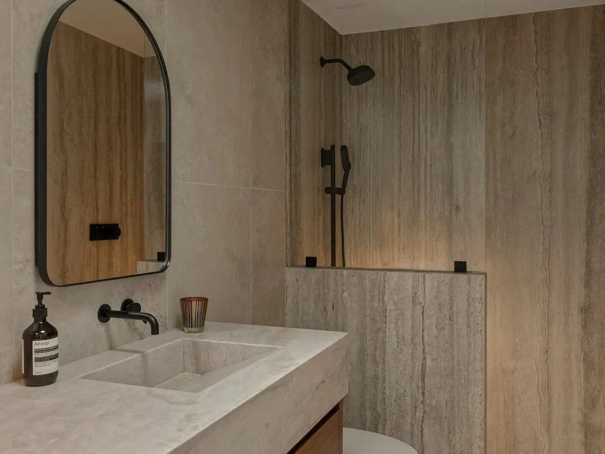 Stone-tiled bathroom with wooden vanity and matte black fixtures