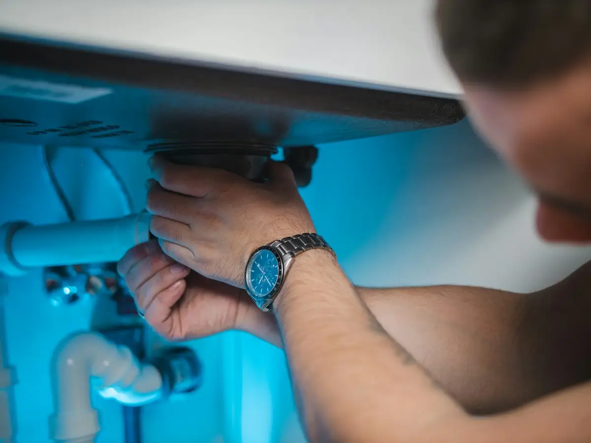 Plumber clearing a drain under a sink