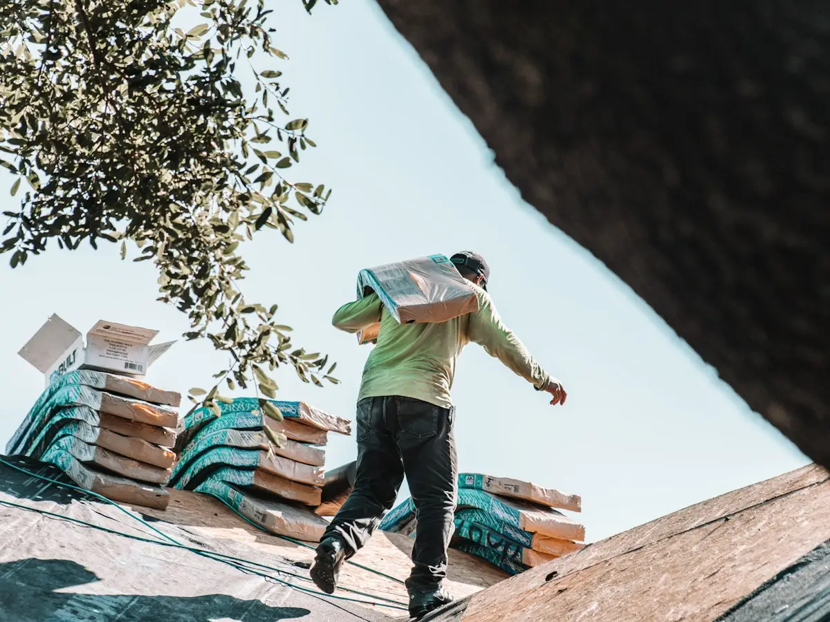 Roofer carrying a bundle of shingles across a roof