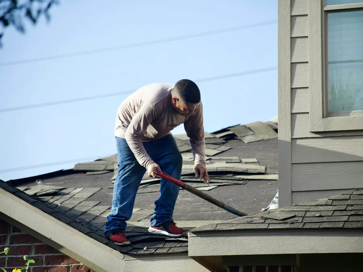 Roofer removing damaged shingles